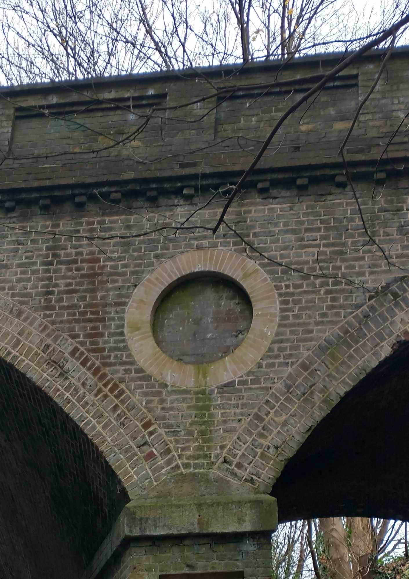 Section of a brick bridge arch with a circular decorative insert.